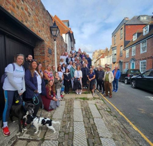 A group of 40 peoples stand on steps before the Hastings Legal Walk and smile at the camera.